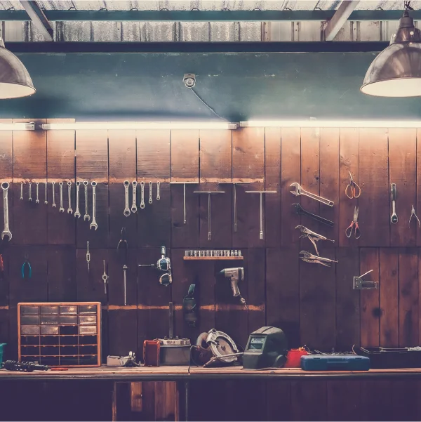 Un établi dans un cabanon ou garage, orné d'outils variés soigneusement disposés sur sa surface.